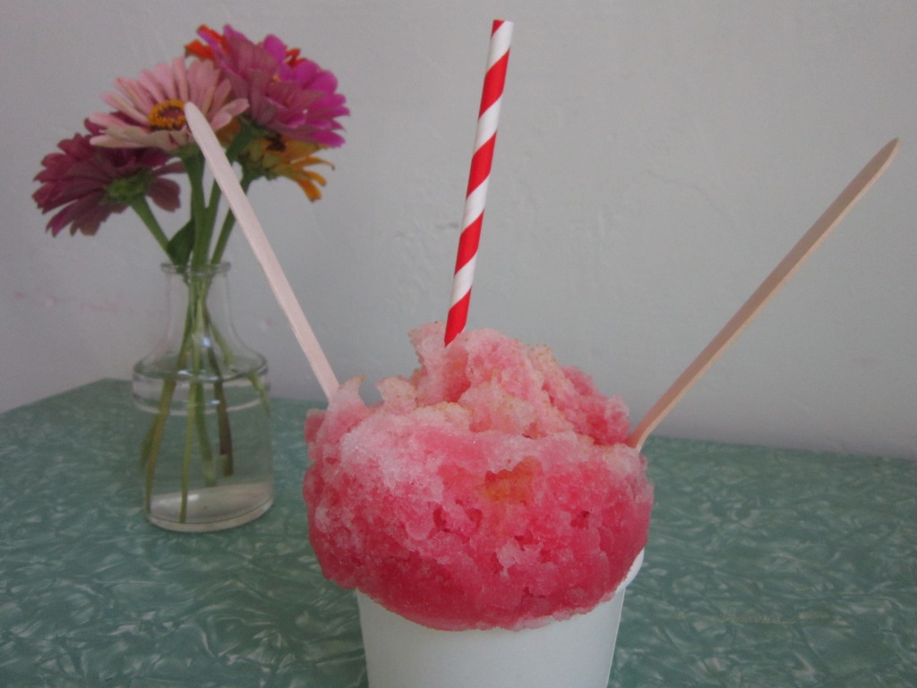 a generous portion of passion fruit and raspberry shaved ice in front of a vase of fresh flowers at Katiebug's in OKC